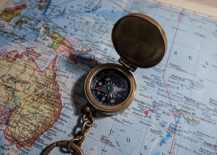 round brass compass on world map