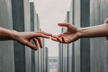 Two hands reaching for each other with columns in the background